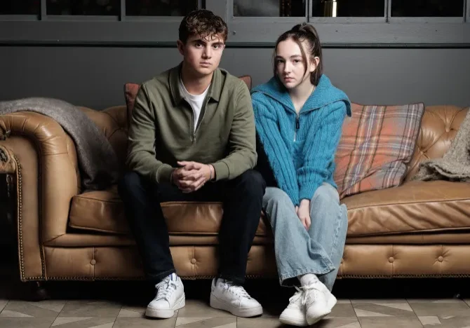 one young male and one young female sitting next to each other on the couch