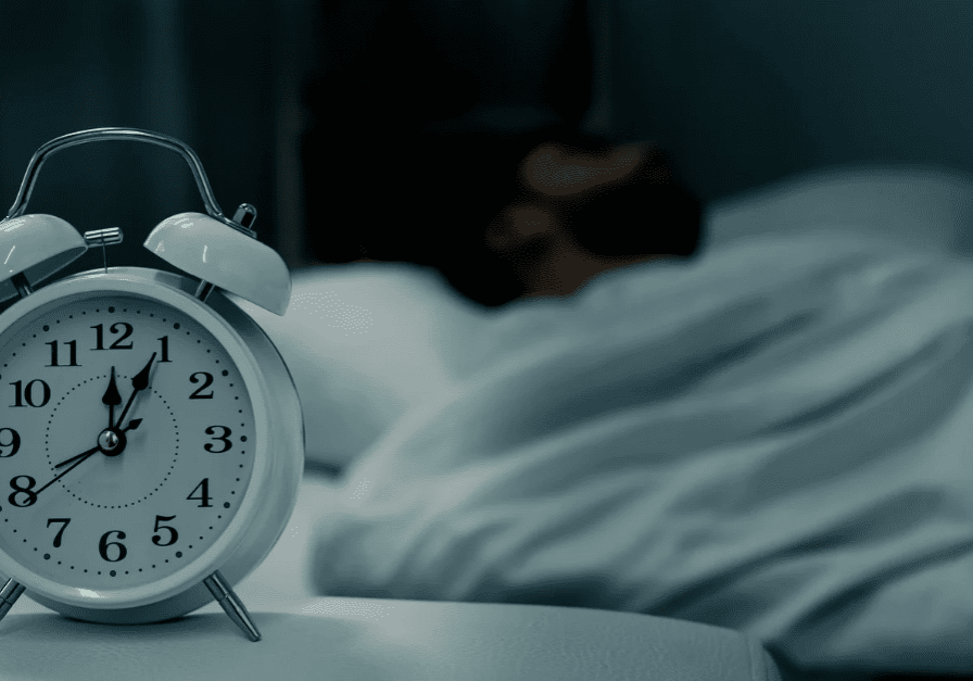 Alarm clock with man sleeping in background